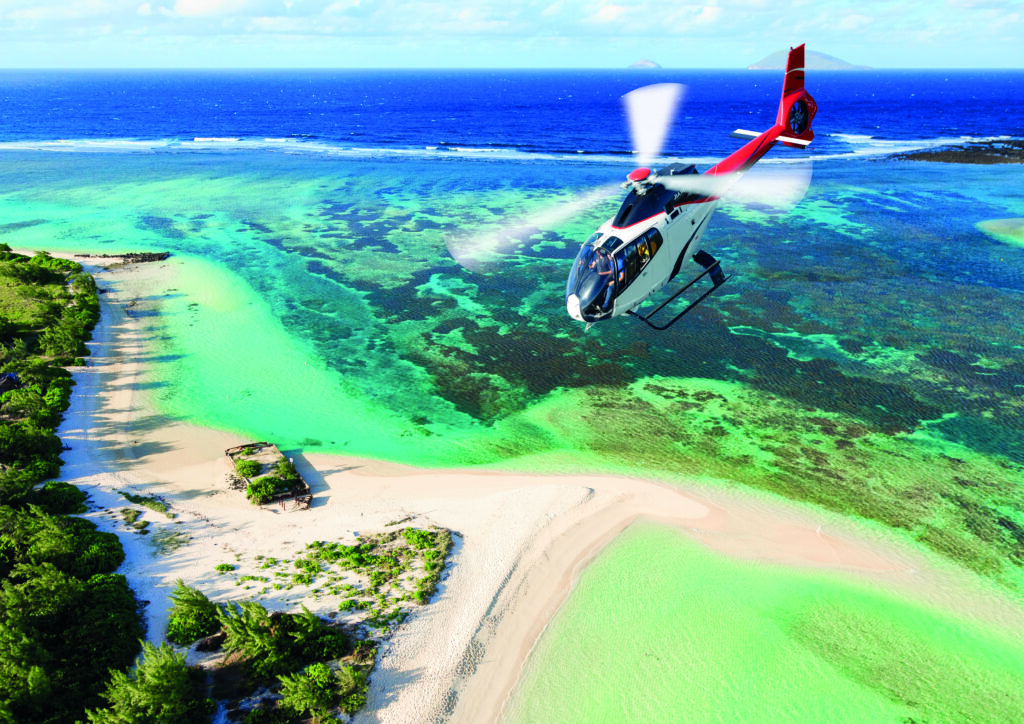 Helikopter przelatujący nad krystalicznie czystą wodą i plażą Flat Island na Mauritiusie.
