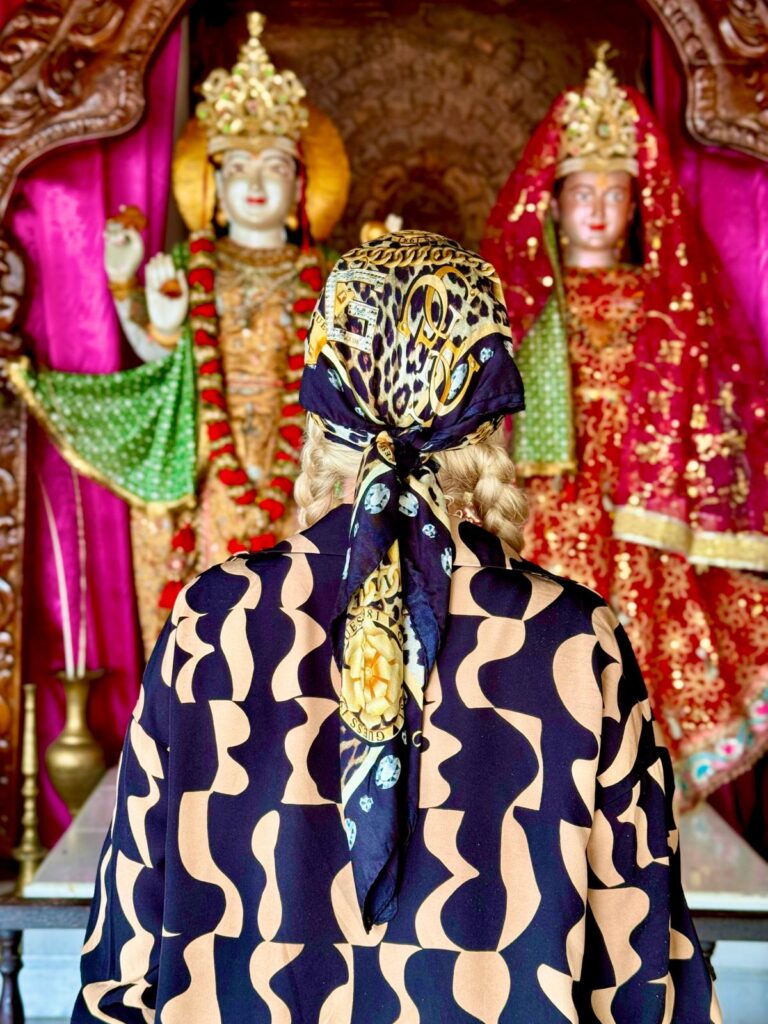 Kobieta w stroju tradycyjnym na Mauritiusie z wzorem giraf przed ozdobnymi posągami